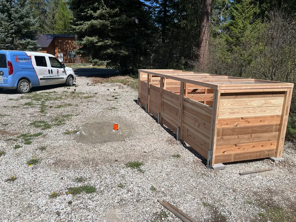 Custom cedar compost enclosure installed on a gravel pad near Deer Park, with the Rim Rock Property Plus van in the background
