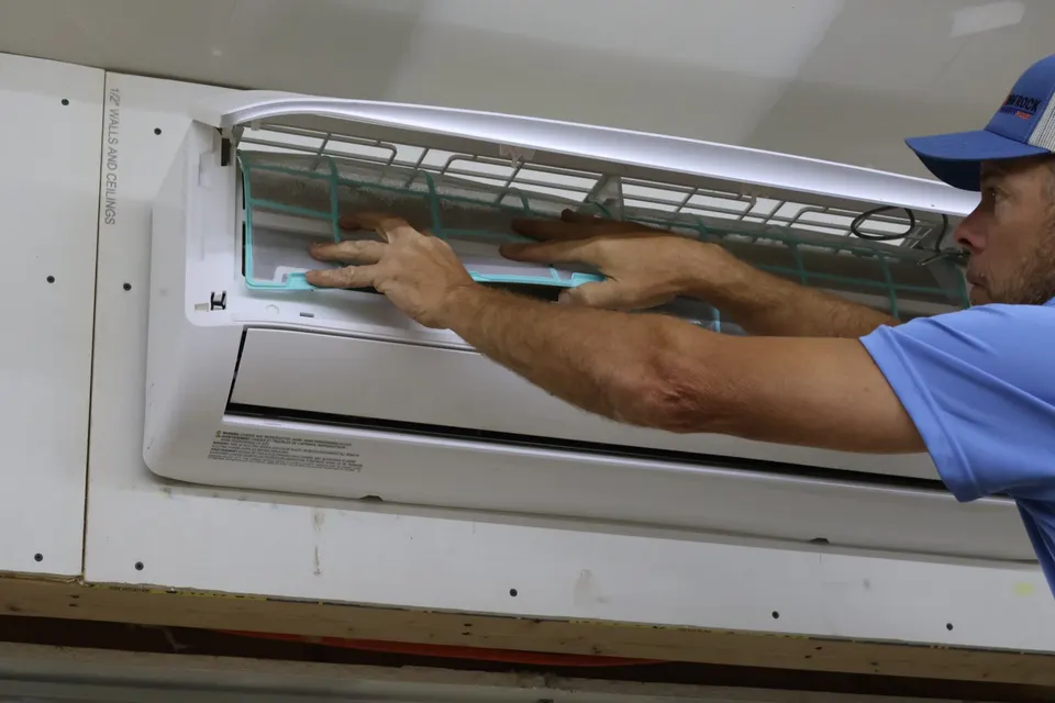 Rim Rock technician removing the filter screen from a wall-mounted ductless mini-split